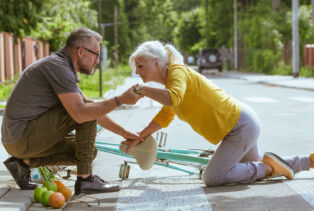 Un homme aide un femme à se relever après une chute à vélo dans la rue